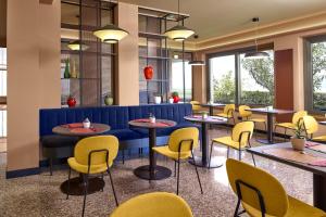马尔切西内Residence Lido Hotel的一间带桌子和黄色椅子的餐厅