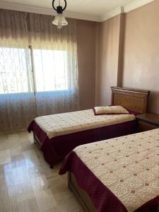 安曼شقة مفروشة للايجار في عمان شارع الجامعة الاردنية的一间卧室设有两张床和窗户。