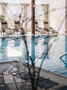 Sankt Lorenzen im LesachtalAlmwellness-Resort Tuffbad的一个带椅子的游泳池,水中反射