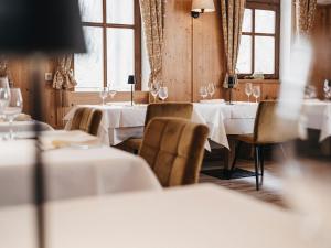 Sankt Lorenzen im LesachtalAlmwellness-Resort Tuffbad的餐厅设有白色的桌椅和窗户。