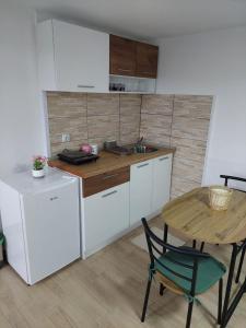 下米拉诺瓦茨Apartmani Kuljanin的厨房配有白色橱柜、桌子和水槽。