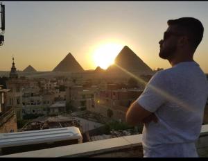 开罗City pyramids inn的站在一座建筑物顶端看金字塔的人