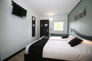 沙特尔Enzo Hotels Chartres Mainvilliers by Kyriad Direct的卧室配有一张床,墙上配有电视
