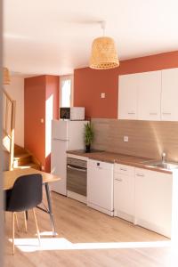 Rive-de-GierKASA DUPLEX - Climatisation - Balcon - Parking Privé的厨房配有白色橱柜和木桌