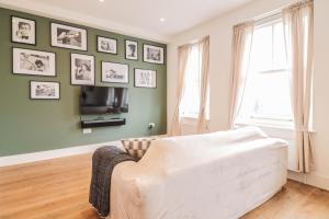 伦敦Modern & spacious 1 bedroom Clapham Junction flat的客厅配有沙发和墙上的照片