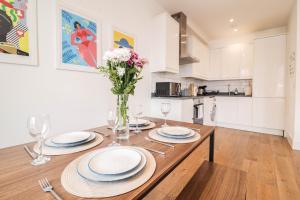 伦敦Modern & spacious 1 bedroom Clapham Junction flat的厨房配有带盘子和鲜花的木桌