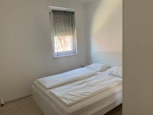 福纽德Vitorlás Apartman的窗户客房内的一张白色床