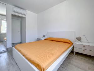 瓦拉泽Nuovo Bilocale con posto auto的白色卧室配有带橙色毯子的床