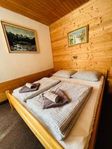 Liptovský OndrejChalupa u Porubäna的木制客房内的两张床和毛巾