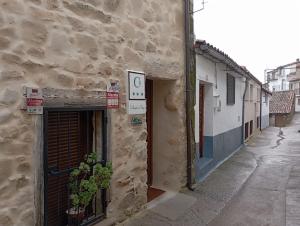 VillamielRestaurante & Hotel Rural El Mirador de Trevejo的石头建筑,有门和标志