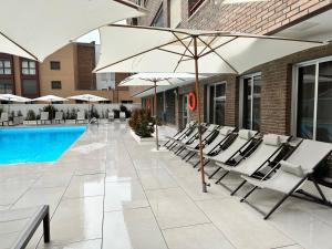 马德里JUAN BRAVO Apartamento a estrenar con PISCINA的一组椅子和遮阳伞,位于游泳池旁