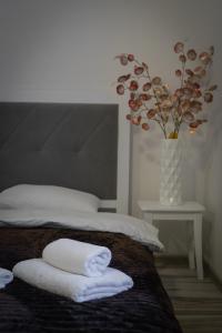 文尼察TREND HOUSE Apartments & Hostel的一间卧室配有带毛巾的床和鲜花花瓶