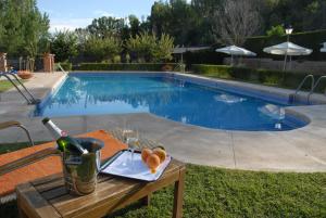 锡古恩萨Molino de Alcuneza Relais & Châteaux的游泳池旁的桌子,上面有一瓶葡萄酒和玻璃杯