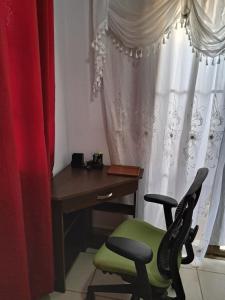 马那瓜Acogedora Casa的一张桌子和一张靠窗的绿色椅子