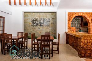 坎昆VIca Guest House con piscina en la entrada de la Zona Hotelera的餐厅设有木桌和椅子,拥有砖墙