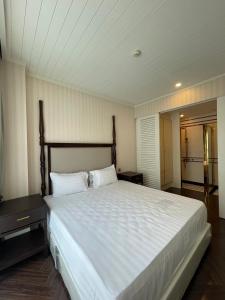 纳仲天Grand Florida BeachFront Resort NaJomtien Pattaya的一间卧室配有一张带白色床单的大床