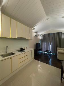 纳仲天Grand Florida BeachFront Resort NaJomtien Pattaya的一间带白色橱柜的厨房和一间客厅