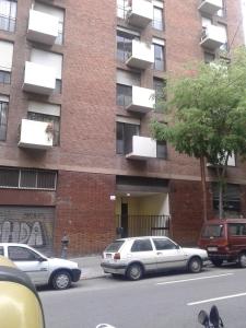 巴塞罗那布鲁斯达圣家堂旅馆的一座砖砌建筑,前面有汽车停放