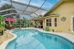 那不勒斯Pet Friendly Pool Home in River Reach of Naples FL的一个带可伸缩屋顶的游泳池和一个房子