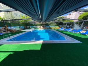 阿拉尼亚Kadeer Hotel的一座带蓝色椅子的游泳池和一座建筑