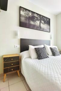 桑特费柳德吉克索尔斯HOSTAL RIGAU的一间卧室配有一张白色的床和黑色床头板