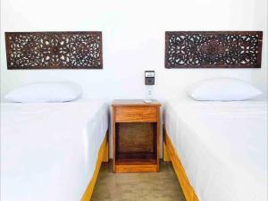 埃斯孔迪多港Villa Ocean的两张床位于一间房间,中间设有床头柜