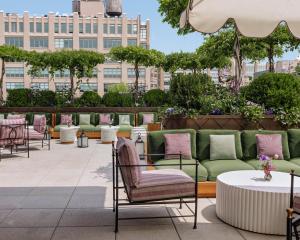 纽约Hotel Barrière Fouquet's New York的庭院设有绿色和粉红色的椅子和桌子
