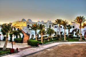 赫尔格达阿拉贝拉海岸度假酒店的一座白色的大建筑,前面有棕榈树