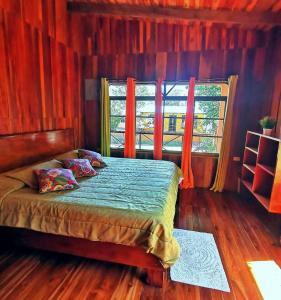 蒙泰韦尔德哥斯达黎加Villa El Nido Monteverde的一间卧室配有一张带红色窗帘的床和一扇窗户
