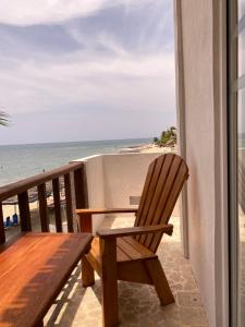 RincónHotel Casa Sattva- Bed & Breakfast的一张木椅,位于一个俯瞰着海滩的阳台