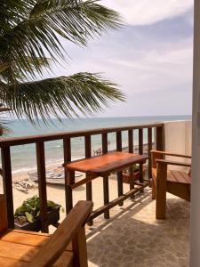 RincónHotel Casa Sattva- Bed & Breakfast的俯瞰海滩的阳台配有木桌和长椅。