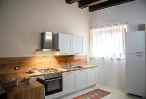 阿格里真托PALAZZO ZUPPARDO LUXURY的厨房配有白色橱柜、水槽和冰箱。