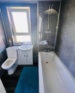 罗塞斯Park Road Holiday Home的浴室配有卫生间、盥洗盆和浴缸。