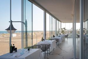 卡奥莱Unico Hotel Caorle的一间带桌椅的餐厅以及海滩