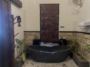 SemayaAKSARA nusa penida的浴室设有黑色浴缸,种植了植物