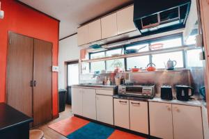 气仙沼市SLOW HOUSE kesennuma - Vacation STAY 31901v的厨房设有红色的墙壁和白色的橱柜