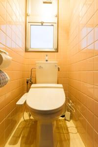 松山渡高别墅式酒店的浴室设有白色卫生间和窗户