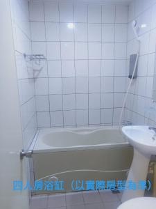 基隆永豐旅社的白色瓷砖浴室设有浴缸和水槽