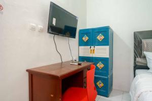 西冷KoolKost Syariah @ Citraland Puri Serang的客房设有一张桌子、一台电视和一张红色椅子。