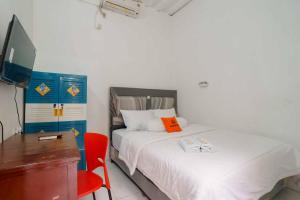 西冷KoolKost Syariah @ Citraland Puri Serang的一间卧室配有一张床、一张桌子和一把红色椅子
