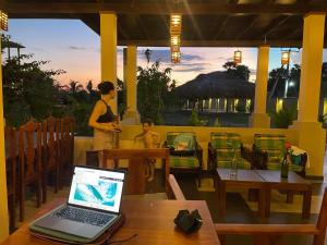 阿鲁甘湾Paddyway Resort的坐在餐厅里的女人,桌上有笔记本电脑