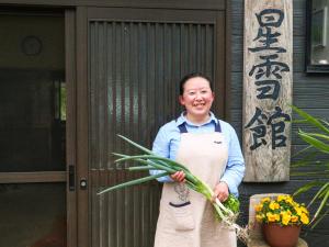 仙北noukanoyado seisetsukan的围裙里拿着一束鲜花的人