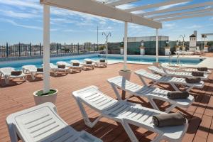 塞维利亚艾克斯塞维利亚玛卡瑞纳酒店的一个带躺椅的甲板和一个游泳池