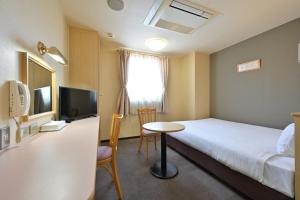 和歌山和歌山第二富士酒店的一间酒店客房,配有一张床铺、一张桌子和一台电视
