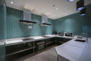 上海TULU途楼公寓(上海斜土路店)的厨房设有绿色瓷砖墙壁和不锈钢用具