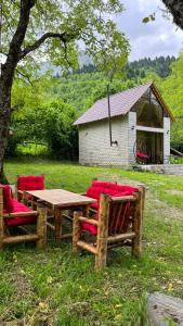 OniIano的一张木桌,上面有红色椅子,坐在草地上