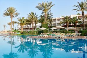 阿加迪尔Iberostar Founty Beach All Inclusive的一个带椅子和棕榈树的游泳池以及酒店