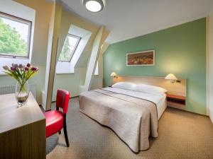 布拉格迈克酒店的一间卧室配有一张大床和一张红色椅子