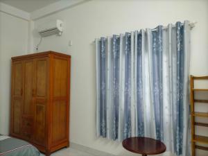岘港TN's House的卧室配有蓝色和白色的窗帘和木制橱柜