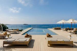 圣埃乌拉利亚ME Ibiza - The Leading Hotels of the World的一个带桌椅的游泳池以及大海